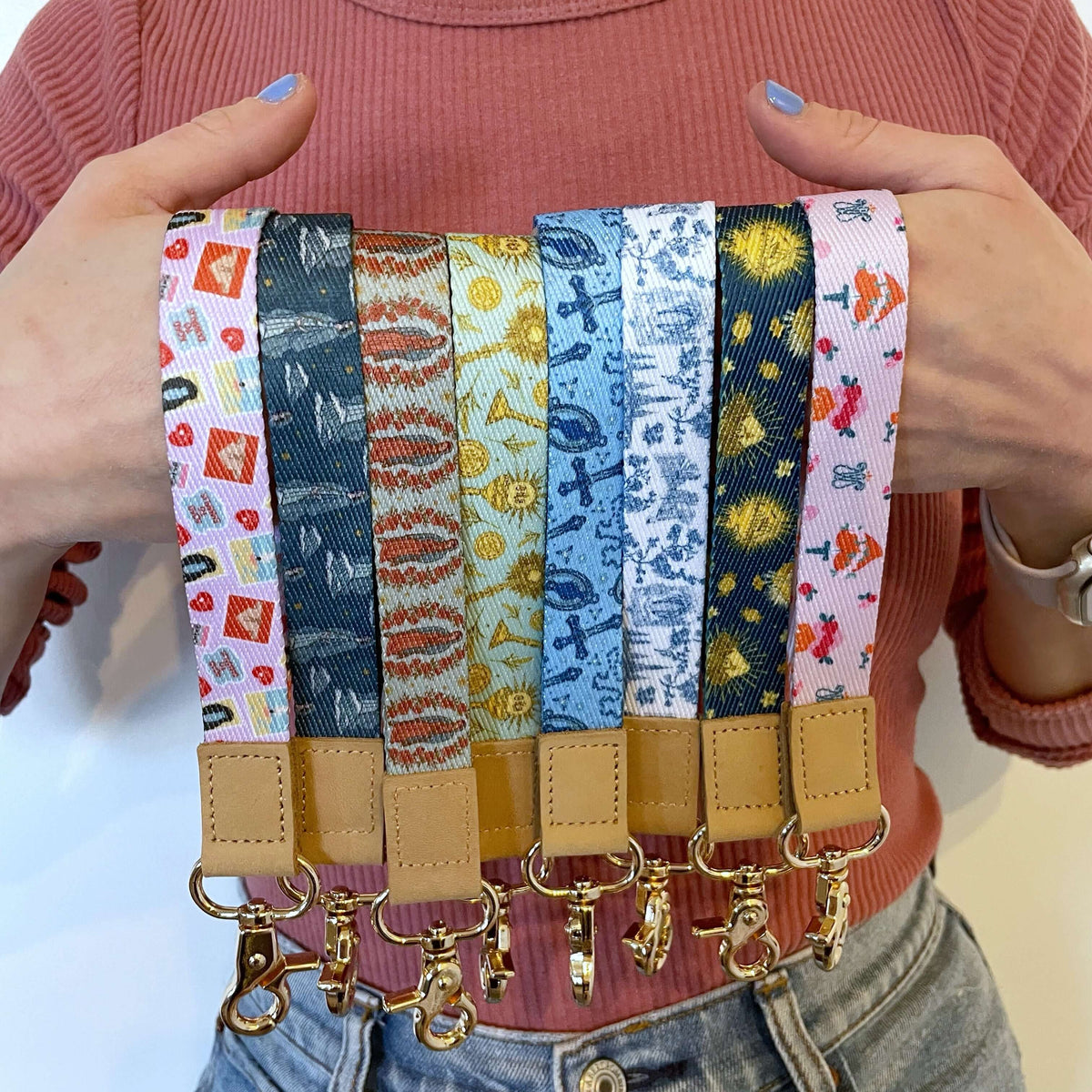 Collection of Catholic wrist lanyards from the Stella Maris Collection, featuring colorful faith-inspired designs and gold clasps.