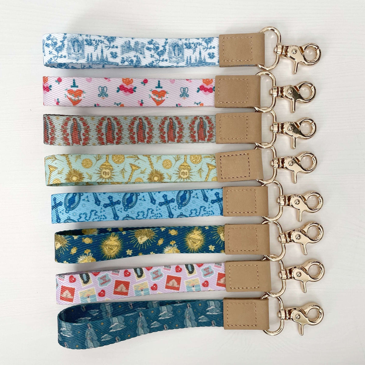 Colorful wrist lanyards from the Holy Hearts Collection with various religious patterns, including Stella Maris and Eucharistic designs.