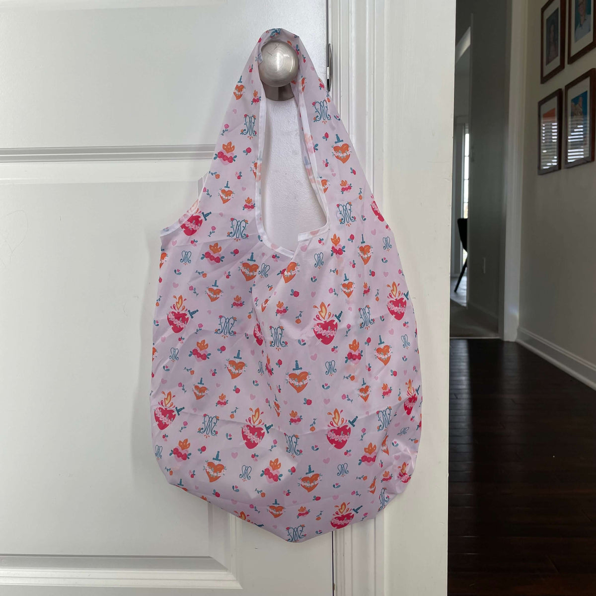 Catholic reusable grocery bag with Auspice Maria design, hanging on a door handle, made from 190T Polyester, 26.5x19 inches.