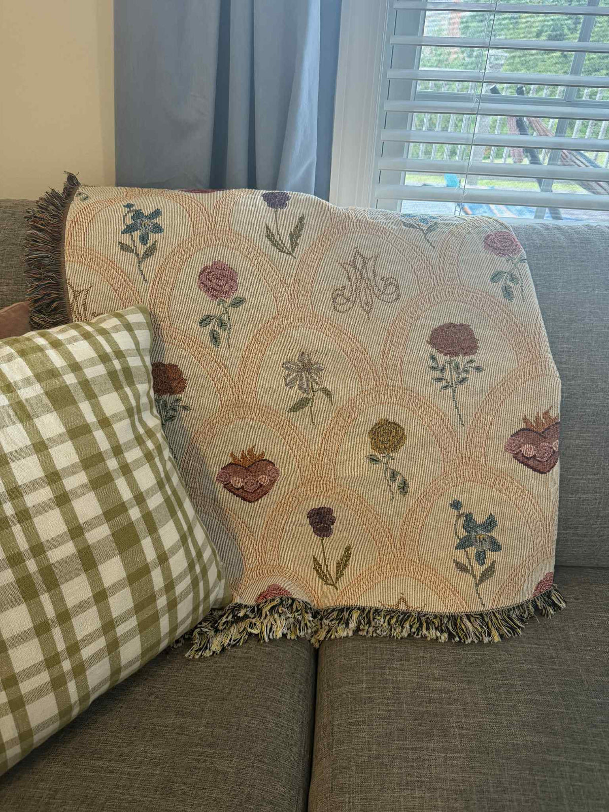 Mary's Sacred Garden Woven Blanket with floral patterns draped over a couch, showcasing religious symbolism and intricate design.
