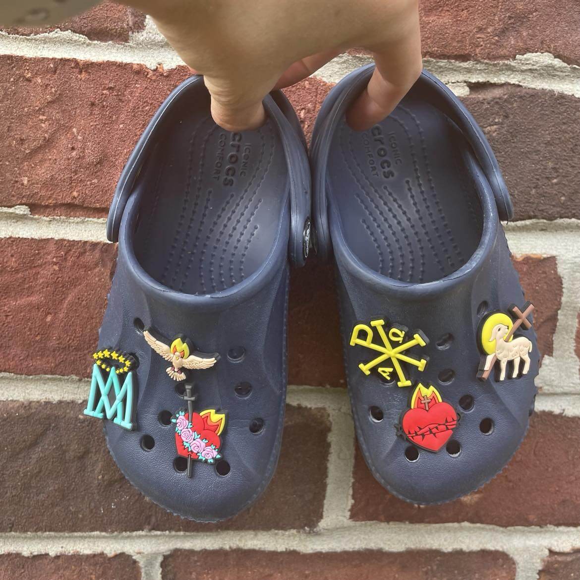 Navy Crocs with Holy Images Catholic charms including Immaculate Heart, Sacred Heart, Holy Spirit Dove, Paschal Lamb, Auspice Maria, Chi-Rho.