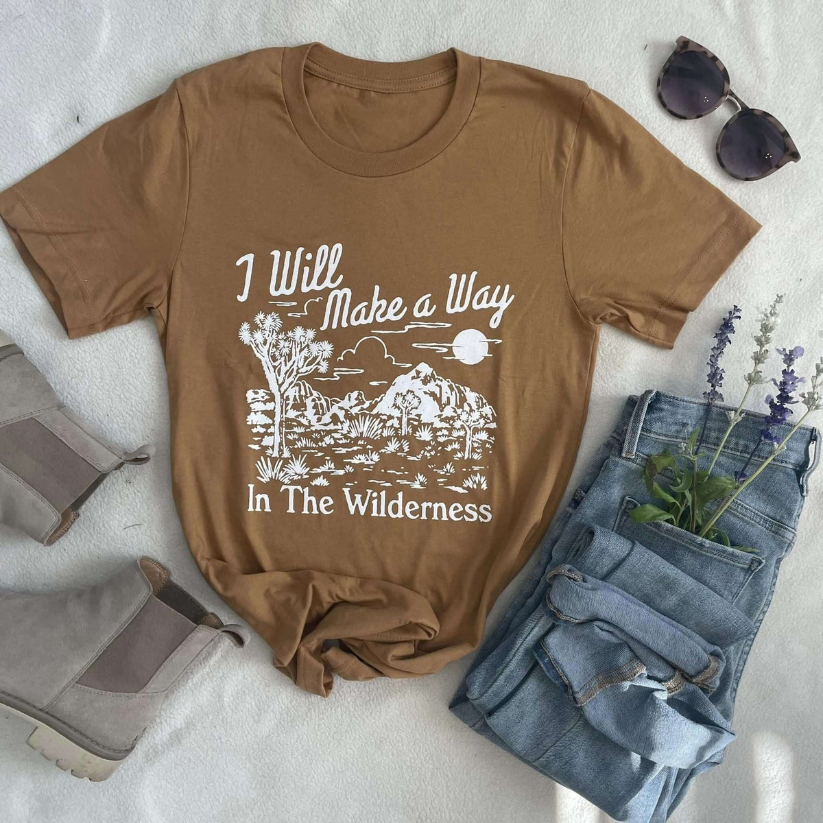 Brown "I Will Make A Way - Isaiah 43:19" desert landscape tee with jeans, boots, sunglasses, and lavender sprigs.