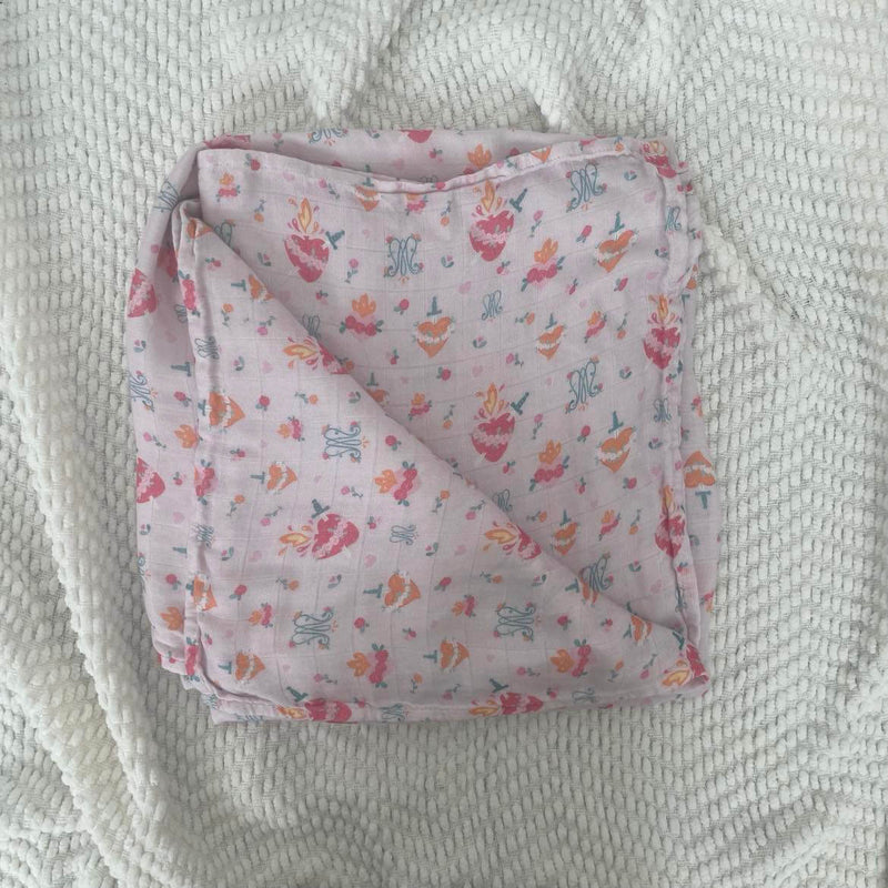 Auspice Maria swaddle blanket made from organic bamboo cotton with religious patterns, folded neatly on a textured surface.