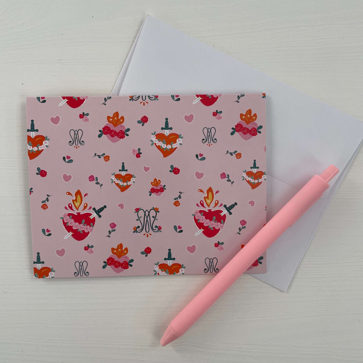 Auspice Maria Catholic note card with heart and floral design, paired with envelope and pink pen on a light background.