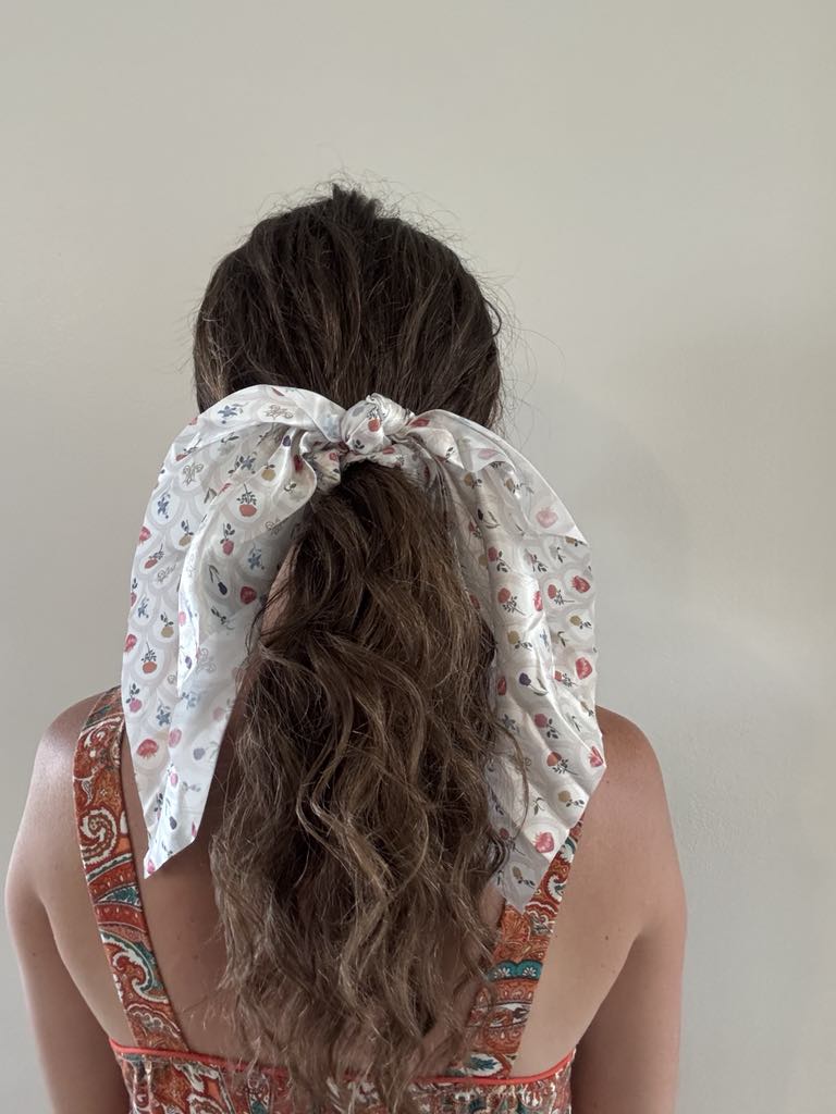 Woman wearing a Catholic satin hanging scrunchie from Mary's Sacred Garden Collection, featuring elegant, timeless Catholic patterns.