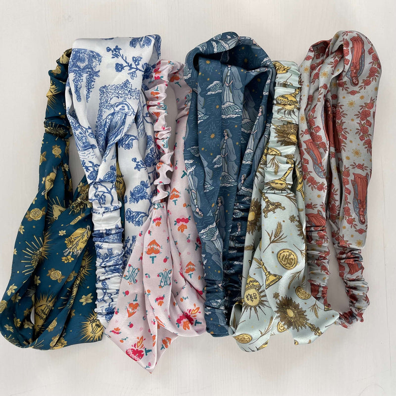 Collection of satin Catholic headbands featuring divine patterns like Guadalupe, designed for comfort and grace in various colors.