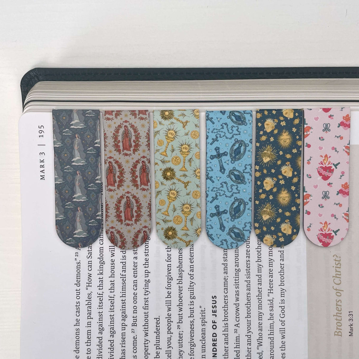 Set of six Catholic magnetic bookmarks with sacred designs on a Bible page, 2 cm x 6 cm, made of 300g C2S paper and soft magnet.