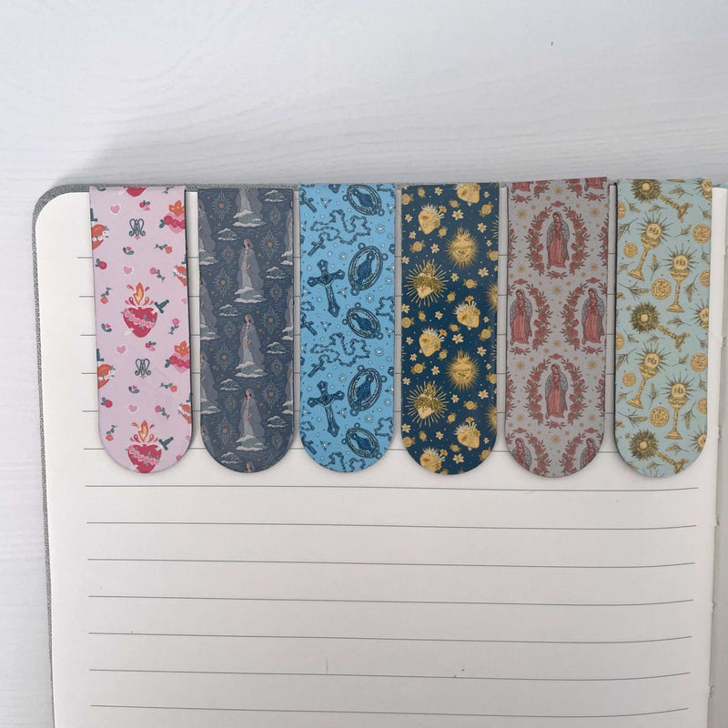 Set of 6 Catholic magnetic bookmarks with colorful sacred patterns on an open notebook page.