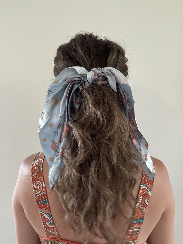 Woman wearing Catholic Satin Hanging Scrunchie from the Guadalupe Collection, showcasing elegant ribbon tied in hair.