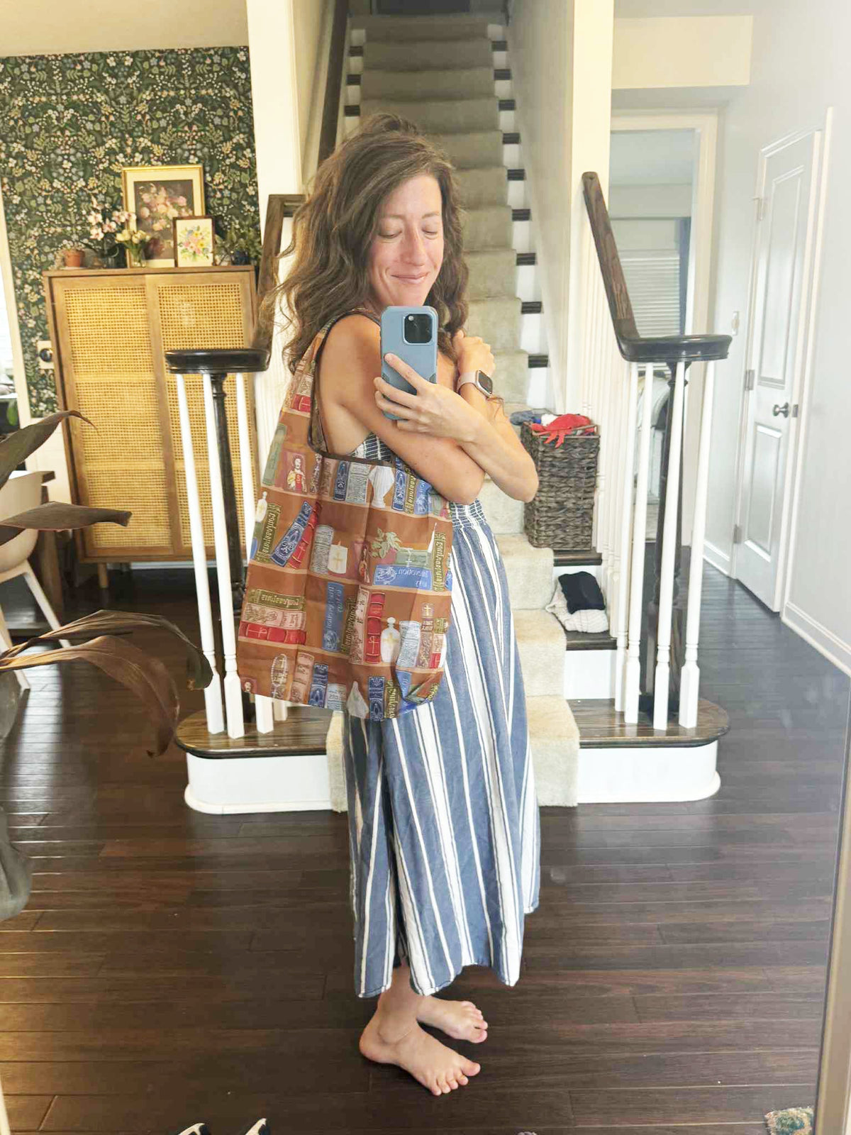 Woman holding a reusable grocery bag with Catholic patterns, standing in a bright interior.