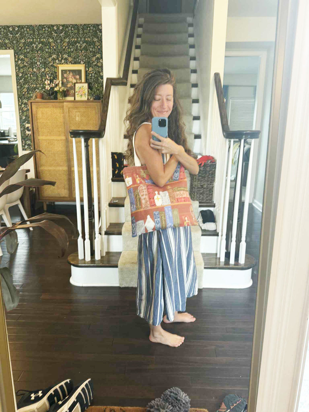 Woman holding a Catholic Library Tote Bag in a home setting