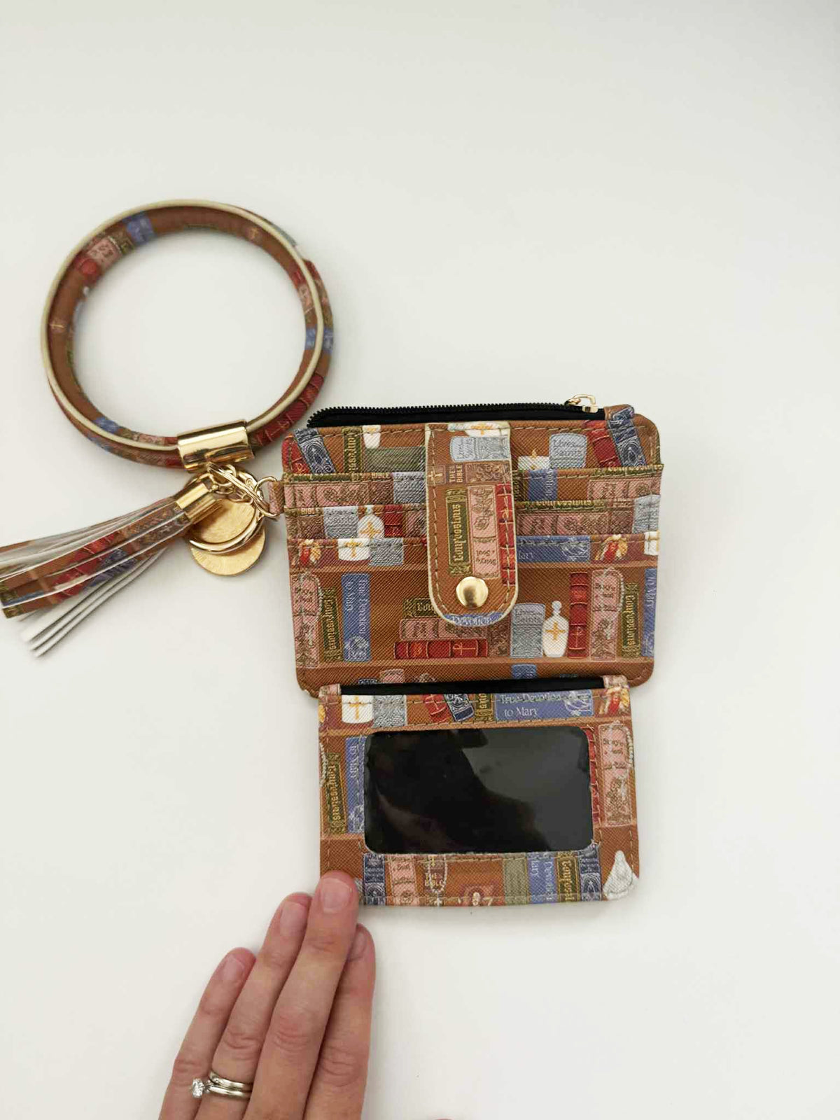 Catholic I.D. Wallet with book pattern, faux leather, featuring hand size comparison, keyring, and tassel attachment.