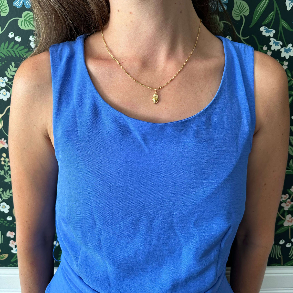 Woman wearing dainty Sacred Heart of Jesus necklace with 18k gold plating on an 18-inch chain, showcasing faith and elegance.