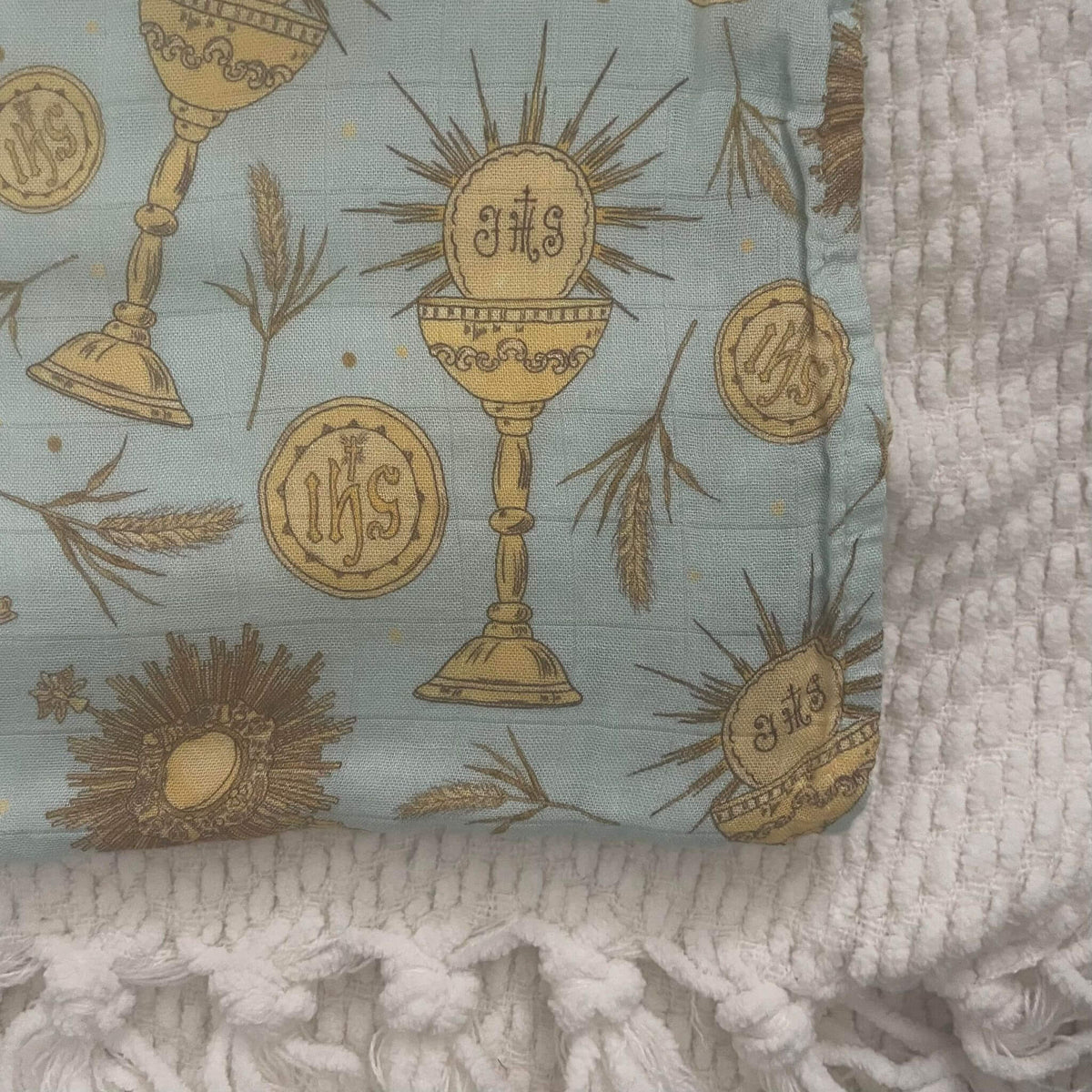 Eucharistic swaddle blanket featuring chalice and IHS motifs on soft fabric, perfect for nurturing baby's faith and comfort.