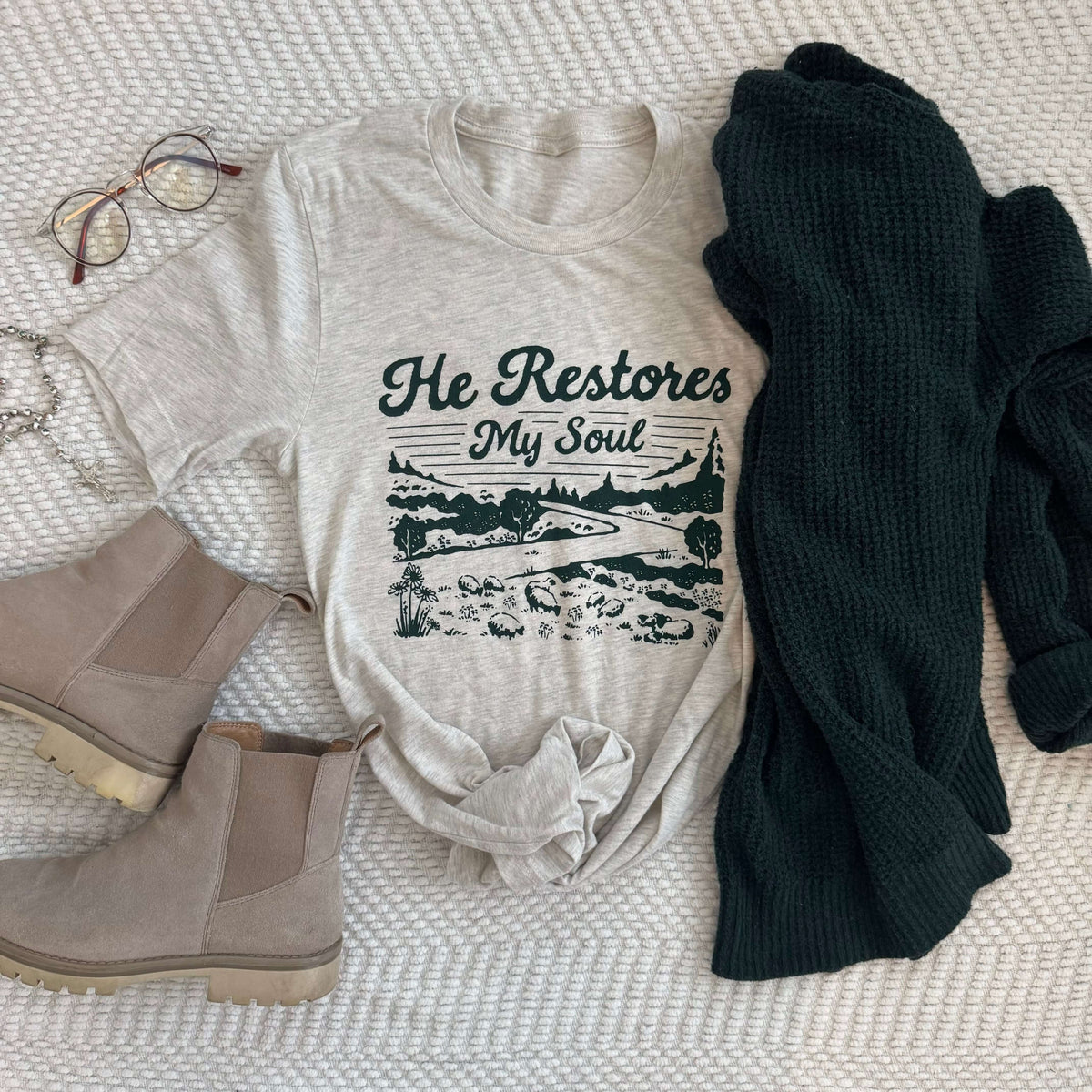 He Restores My Soul Psalm 23 t-shirt with boots and sweater display, Christian apparel for comfort and peace reminder.