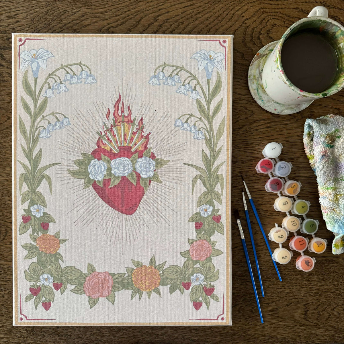 Immaculate Heart of Mary Paint by Number Kit with vintage design, paints, brushes, and cloth on a wooden table.