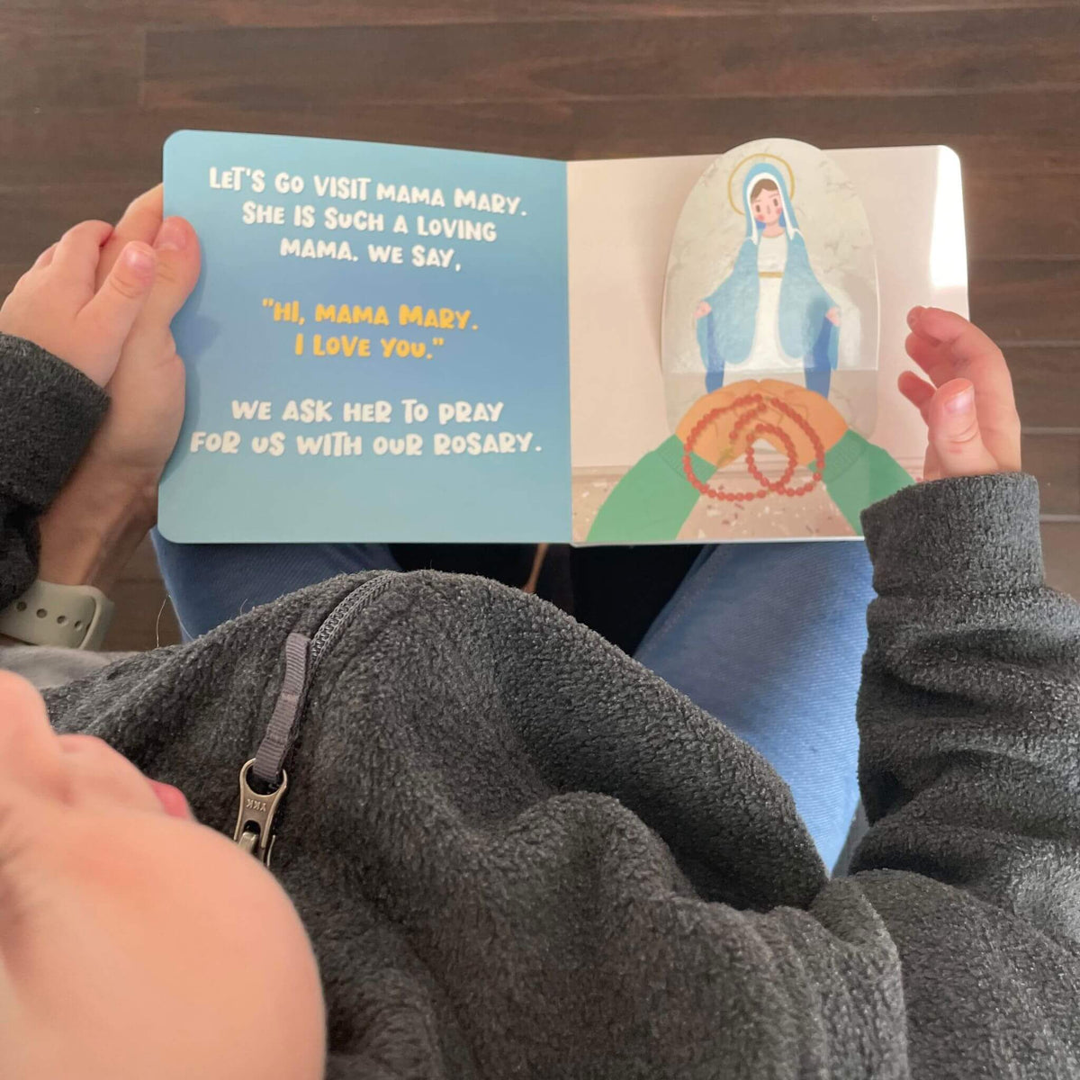 Child reading 'It's Time To Go To Church' lift-the-flap book about visiting Mama Mary, featuring an interactive design.