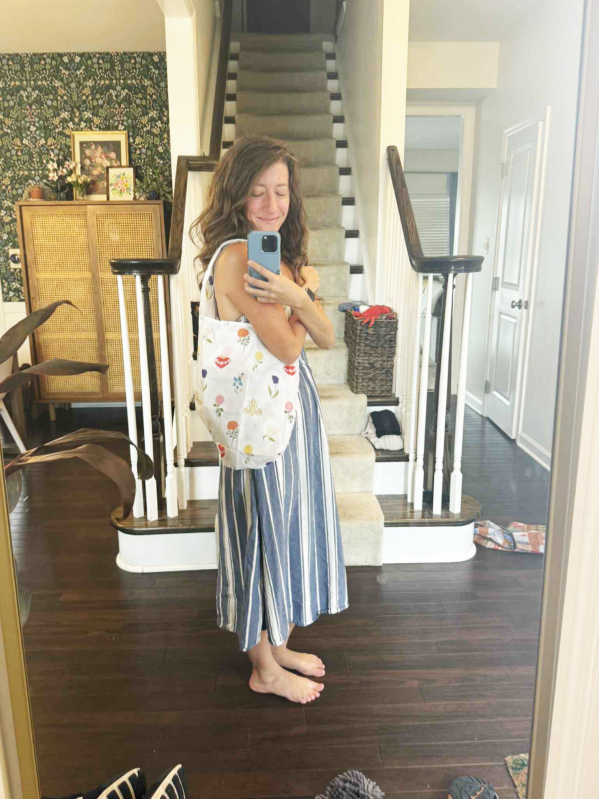 Woman holding Catholic Reusable Grocery Bag from Mary's Garden Collection in home setting, showcasing eco-friendly fashion.