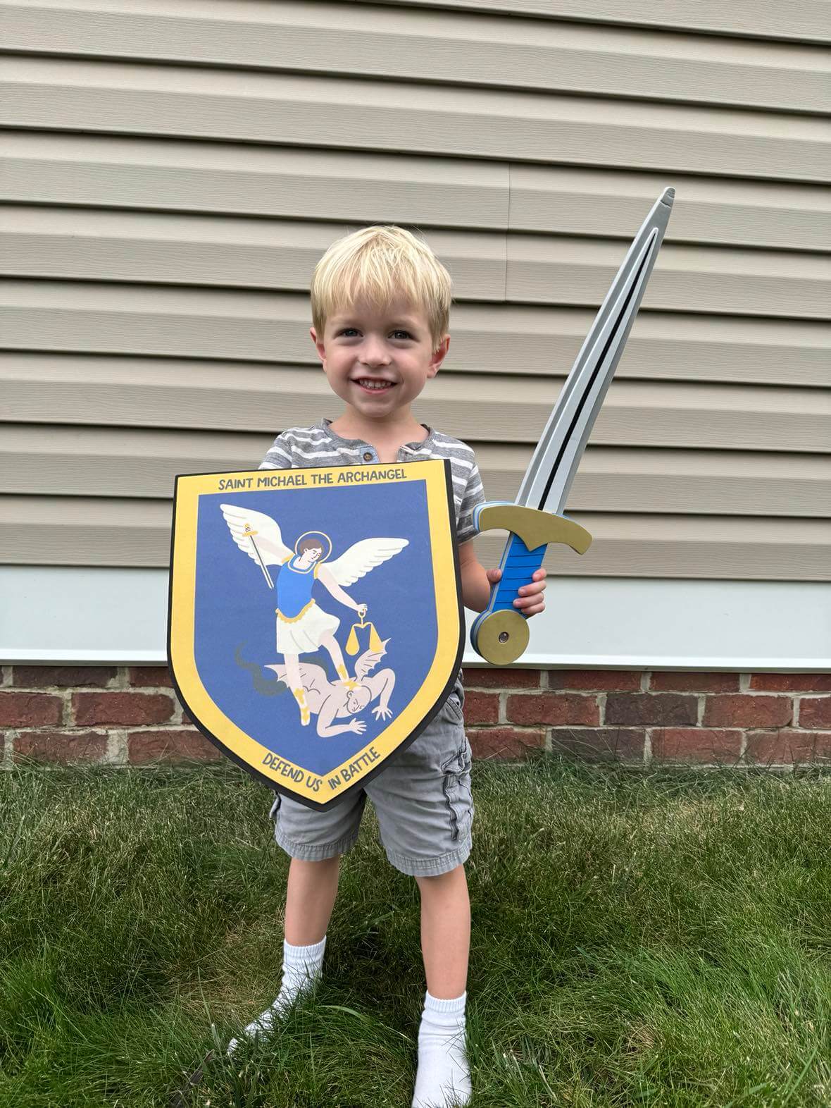 Child holding St. Michael's sword and shield set with archangel design for imaginative play and spiritual inspiration.