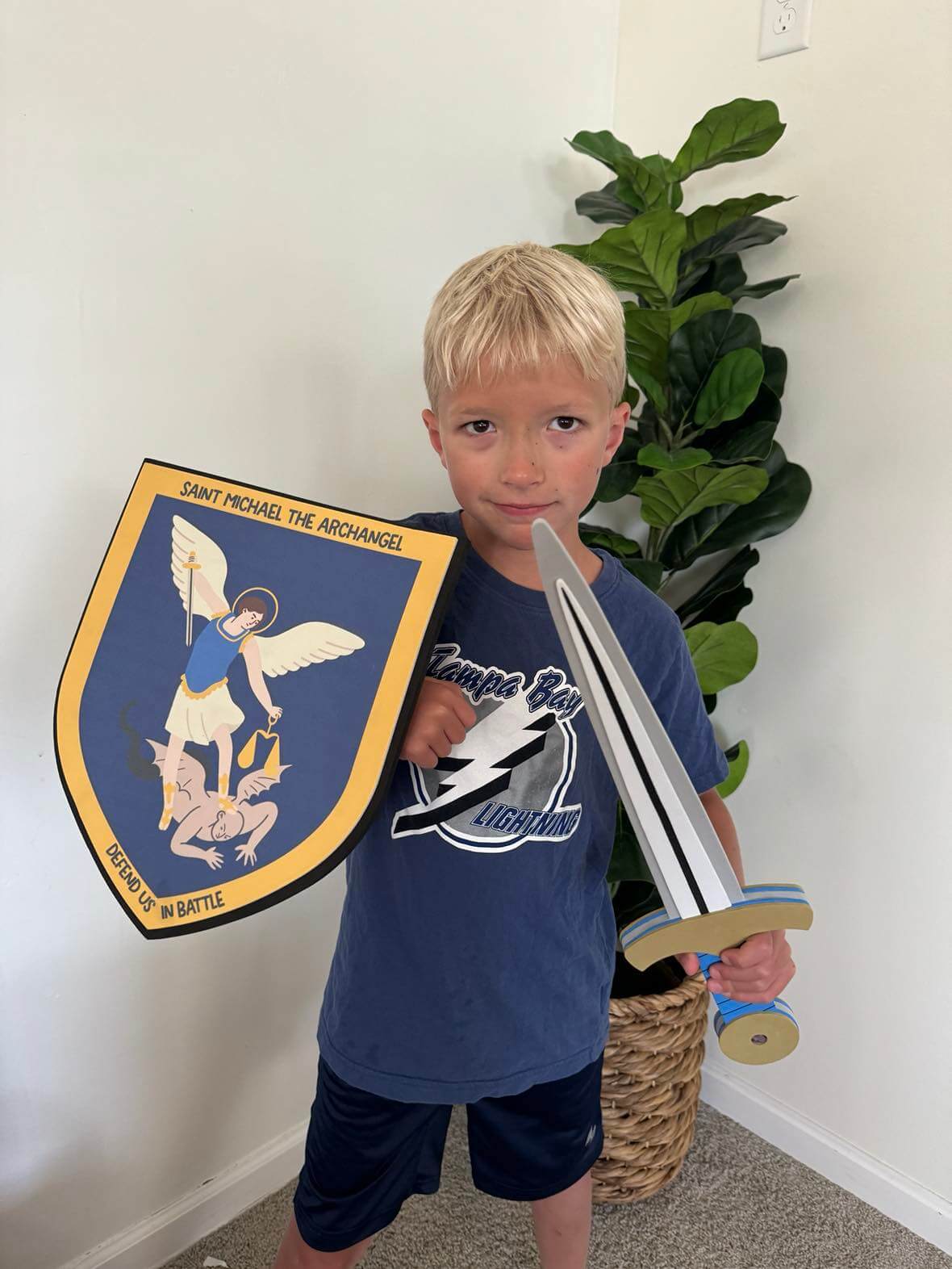 Child holding St. Michael Sword and Shield set with detailed archangel image, inspiring courage and imaginative play.