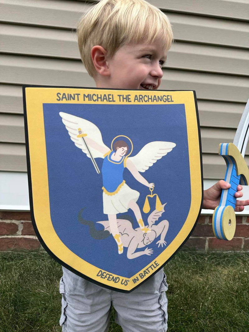 Child holding St. Michael's Sword and Shield set, featuring a detailed image of St. Michael defeating evil, perfect for imaginative play.