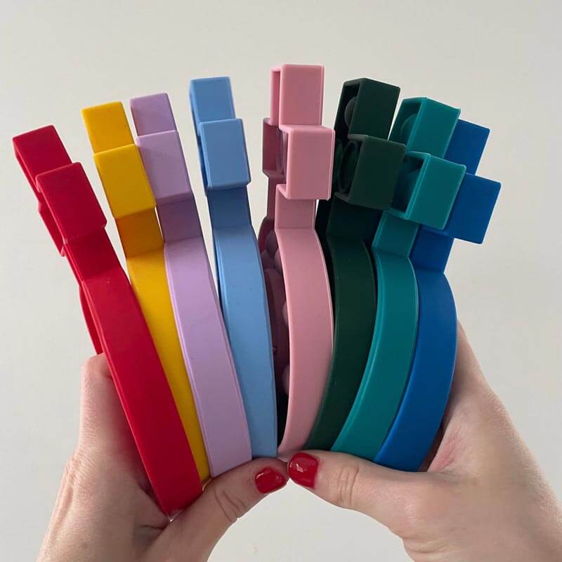Hands holding colorful silicone fidget rosary poppers in various colors, designed for stress relief and focus. Suitable for ages 3 and up.