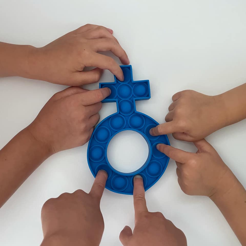 Children's hands using a royal blue Fidget Rosary Popper on a white surface, designed to relieve stress and improve focus.