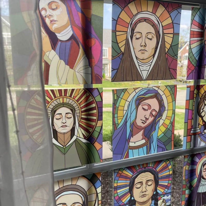 Vibrant stained glass saint window clings on display, featuring nine beloved saints with intricate designs.